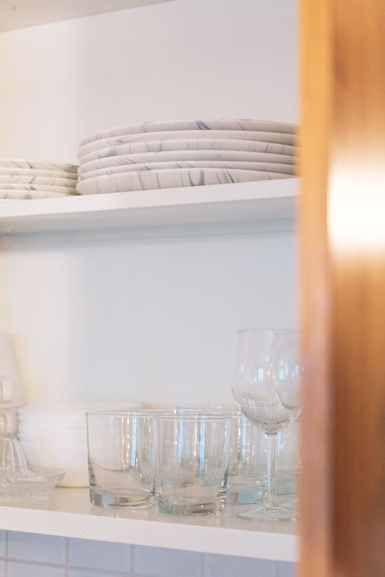Una estantería en la cocina con platos apilados y cristalería.