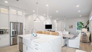 A modern kitchen with white cabinetry, a stainless steel refrigerator, and a central island with a sink. - Luxury Home, Sleeps 16, Palm & Pearl, Pool, Inlet Beach (Inlet Beach)