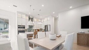 A modern kitchen with white cabinetry, a central island, and pendant lighting. - Luxury Home, Sleeps 16, Palm & Pearl, Pool, Inlet Beach (Inlet Beach)