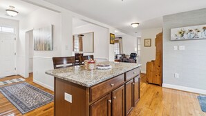 A spacious kitchen with wooden cabinets, a granite countertop, and a built-in island. - Old Town Retreat in Historic Fredericksburg (Fredericksburg)