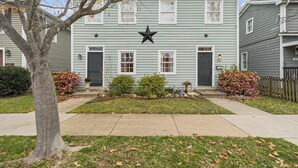 A two-story house with a star on the front, a front door, and a small garden with bushes and flowers. - Old Town Retreat in Historic Fredericksburg (Fredericksburg)