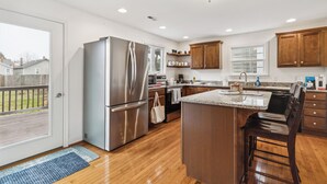 A modern kitchen with stainless steel appliances, wooden cabinets, and a large island. - Old Town Retreat in Historic Fredericksburg (Fredericksburg)