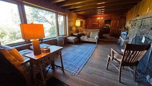 A cozy cabin interior with a wooden dining table, a sofa, a chair, and a fireplace. - Spectacular Rocky Mountain Views + Stream Hiking at this Custom Built Getaway (Chama)