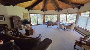 A spacious living room with a high ceiling, large windows, a wooden ceiling, and a cozy seating area with a couch and chairs. - Spectacular Rocky Mountain Views + Stream Hiking at this Custom Built Getaway (Chama)