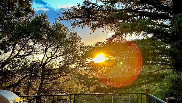 A wooden deck with a grill, wicker chairs, and a view of the sunset through trees. - Spectacular Rocky Mountain Views + Stream Hiking at this Custom Built Getaway (Chama)