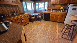 A rustic kitchen with wooden cabinets, a dining table, and a tiled floor. - Spectacular Rocky Mountain Views + Stream Hiking at this Custom Built Getaway (Chama)