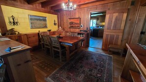 A rustic wooden interior with a dining area, wooden walls, and a chandelier. - Spectacular Rocky Mountain Views + Stream Hiking at this Custom Built Getaway (Chama)
