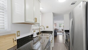 Eine moderne Küche mit weißen Schränken, einer Granit Arbeitsplatte, Edelstahlgeräten und einem Holzschnittbrett.