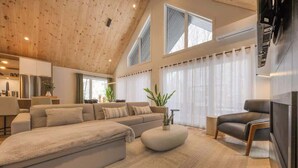 A modern living room with a large sofa, a coffee table, and a TV. - Kos - Domaine du Grand Portneuf - Spa, Nature & Co (Pont-Rouge)