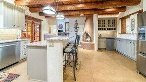 A spacious kitchen with a central island, wooden ceiling beams, and modern appliances. - Private, Peaceful, and Spacious Desert Tucson Villa with Heated Pool and Hot Tub (Tucson)