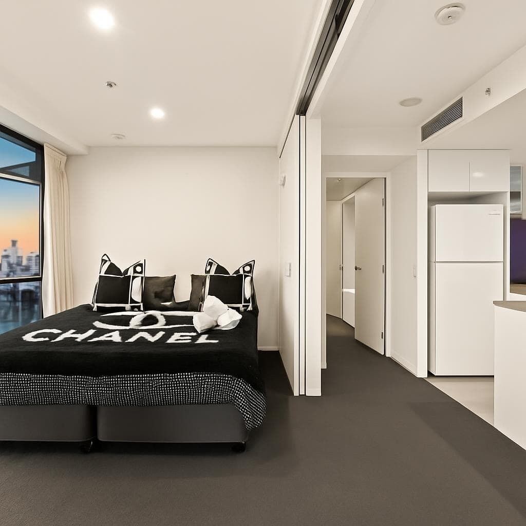 Ein modernes Hotelzimmer mit Bett, einer Küchenzeile und Blick auf die Stadt.