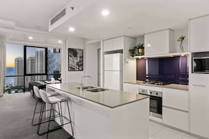 A modern kitchen with a central island, a built-in oven, and a microwave.