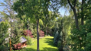 A lush garden with a well-maintained lawn, a wooden gazebo, and dense trees. - Executive Waterfront Loft- 30+ Days (Mississauga)