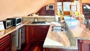 A modern kitchen with a large island, built-in appliances, and a sloped ceiling with skylights. - Executive Waterfront Loft- 30+ Days (Mississauga)