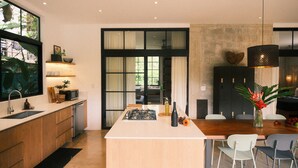 Een moderne keuken met een centraal eiland, inbouwapparatuur en een eethoek met stoelen.