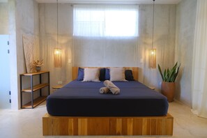 A bedroom with a large bed, wooden headboard, two bedside lamps, a potted plant, and a window with sheer curtains. - Raw. Tropical. Unique. Villa Madom by NP Marino Ballena (Osa)