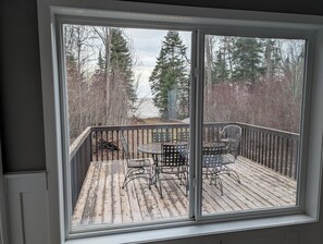 A deck with a table and chairs, overlooking a forested area.