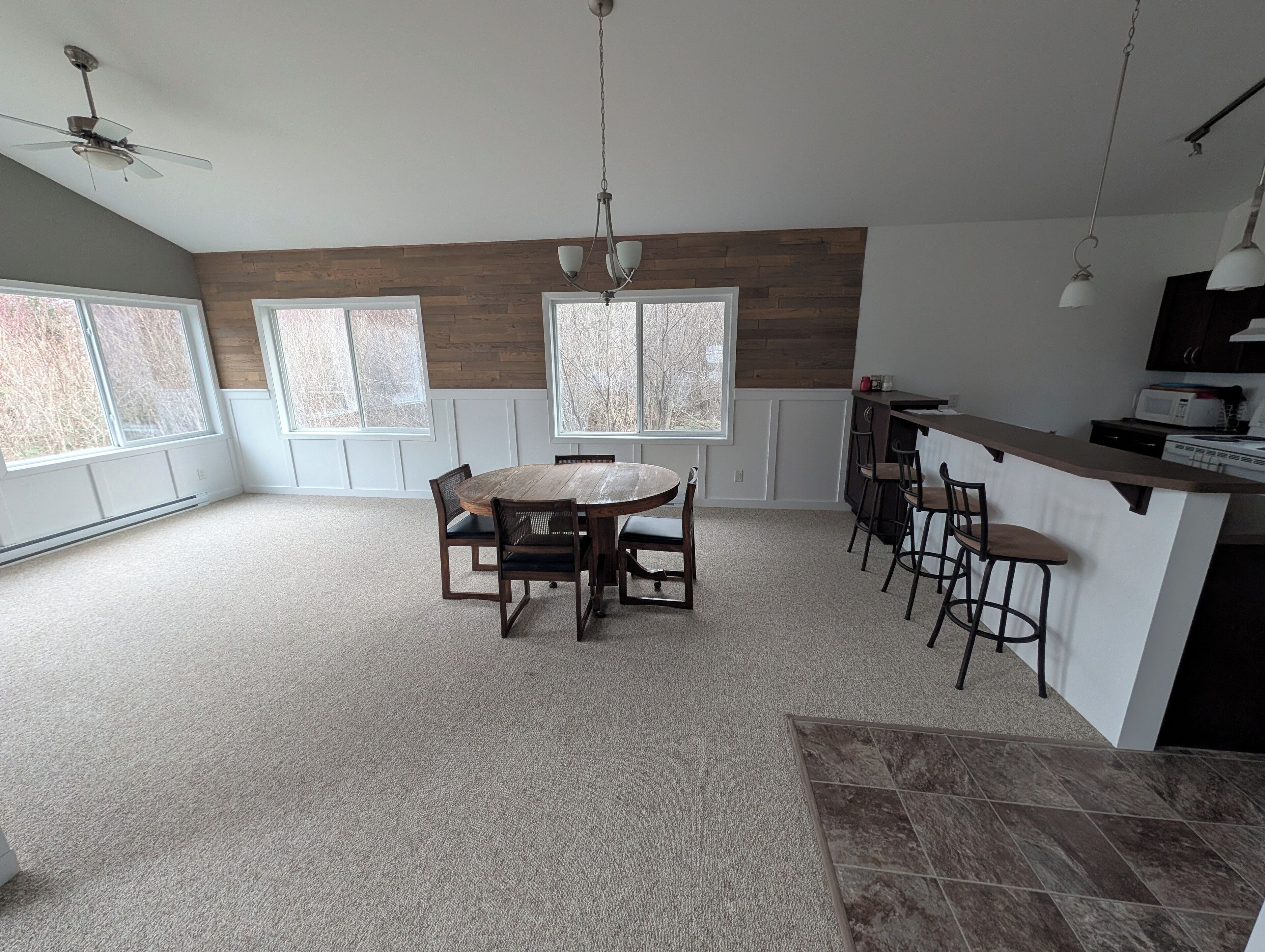 A spacious kitchen with a central island, large windows, and a ceiling fan.