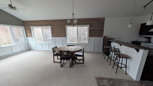 A spacious kitchen with a central island, large windows, and a ceiling fan.