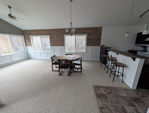 A spacious kitchen with a central island, large windows, and a ceiling fan.