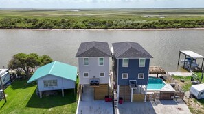 A two-story house with a swimming pool, located near a body of water. - Fish Camp sits on the Colorado River w/pier (Matagorda)
