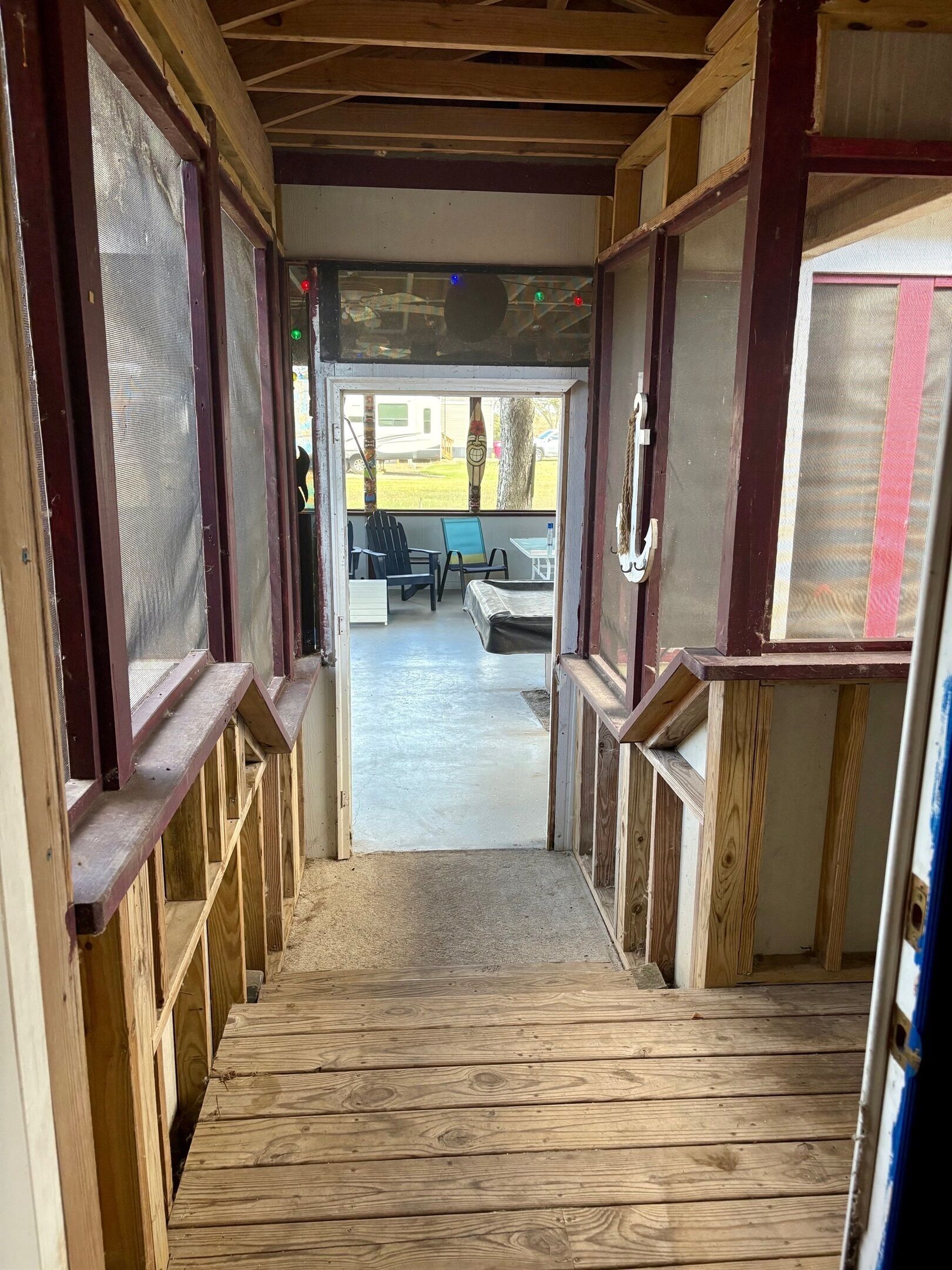 A wooden staircase leading to an outdoor seating area with a view of a grassy field and a parked RV.