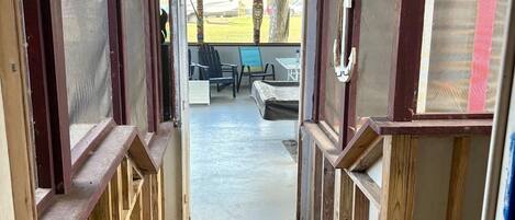 A wooden staircase leading to an outdoor seating area with a view of a grassy field and a parked RV.