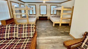 Ein Zimmer mit Etagenbetten, einem Holztisch und einem Stuhl.