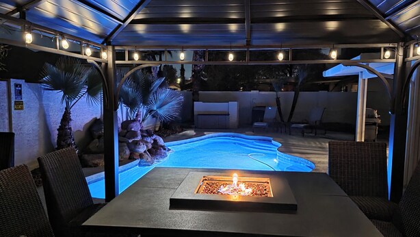 Eine Außenpatio mit Pool, Sitzbereich und Feuerstelle.