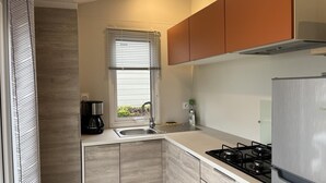 Eine moderne Küche mit einem Gasherd, Edelstahlgeräten und einem Fenster mit Jalousien.