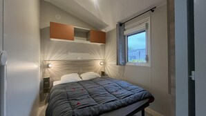 Ein Schlafzimmer mit einem Bett, Nachttischlampen, einem Fenster mit Jalousien und einer Schlafregal-Konstruktion über dem Bett.