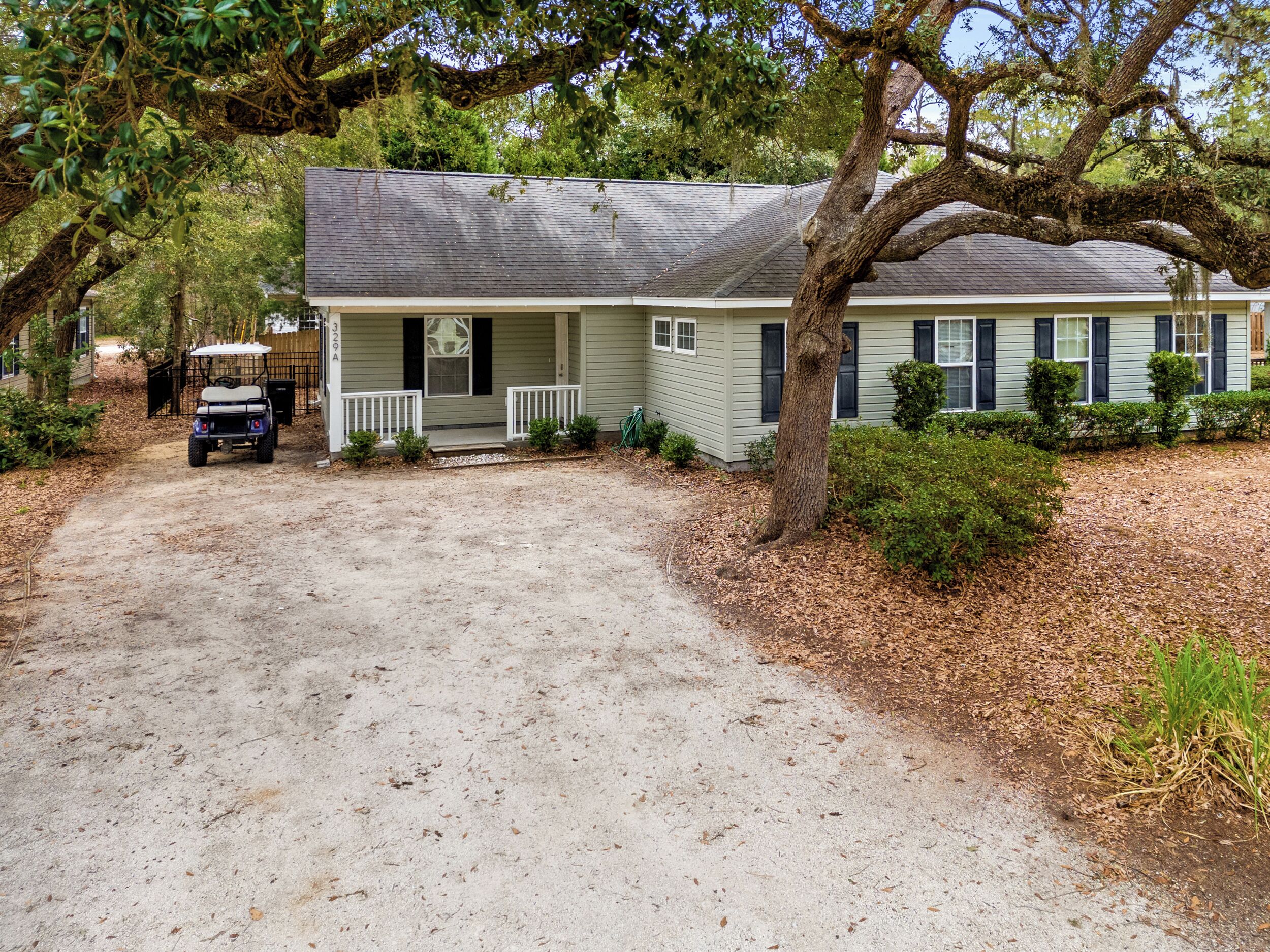 A single-story house with a porch, a driveway, and a golf cart parked outside.