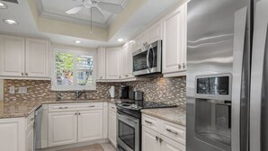 Una cocina moderna con armarios blancos, electrodomésticos de acero inoxidable y un salpicadero de azulejos.