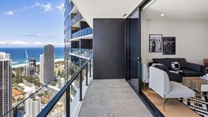 Ein Balkon mit Blick auf die Stadt, eine Couch, ein Couchtisch und eine Tür zu einem Innenraum.