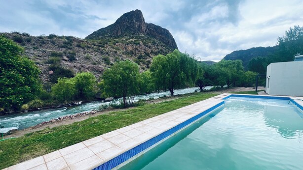 Une piscine avec une rivière et des montagnes en arrière-plan.