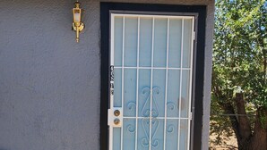 A house with a metal gate, a welcome mat, and a clear sky. - Cozy 1-bedroom studio  in Texico, Nm. (Texico)