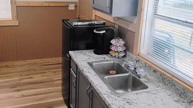 A kitchen with a granite countertop, stainless steel sink, and wooden flooring. - Cozy 1-bedroom studio  in Texico, Nm. (Texico)