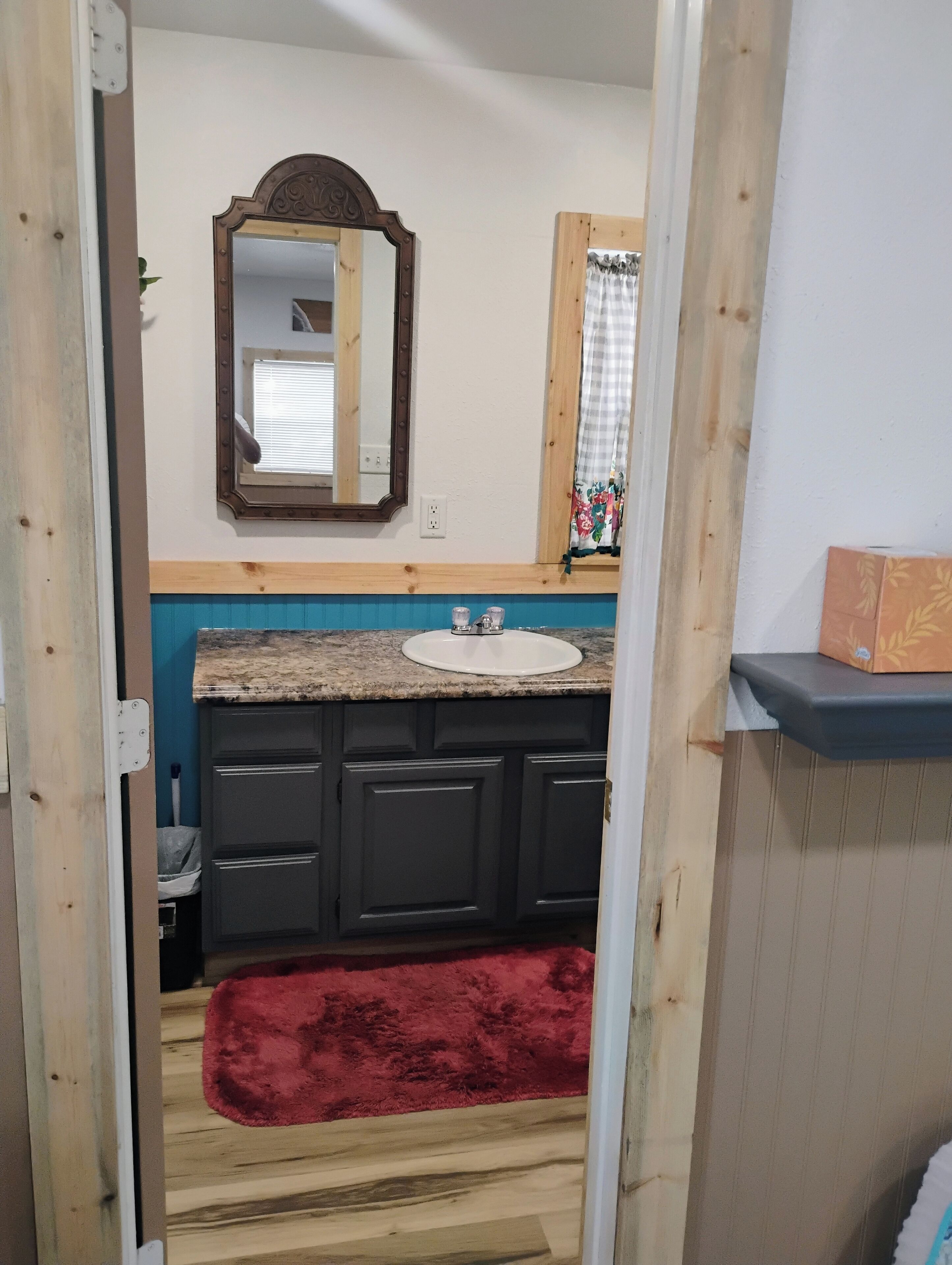 A bathroom with a wooden vanity, a sink, and a mirror.