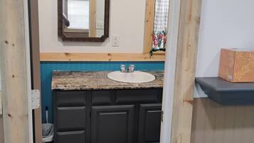 A bathroom with a wooden vanity, a sink, and a mirror.