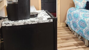 A compact hotel room with a kitchenette, a bed with patterned bedding, and a television mounted on the wall. - Cozy 1-bedroom studio  in Texico, Nm. (Texico)
