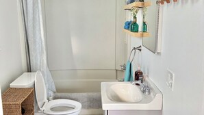A bathroom with a toilet, shower, sink, and a mirror. - Hip Historical First Fl 1BR Downtown King size bed (Brunswick)