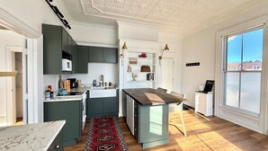 A modern kitchen with dark cabinets, a white countertop, and a red patterned rug. - Hip Historical First Fl 1BR Downtown King size bed (Brunswick)