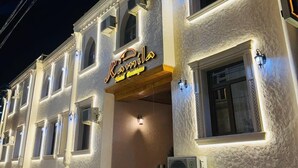 Hotel com estilo arquitetônico clássico, apresentando uma entrada imponente com uma placa, diversas janelas e fachada de pedra.