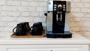 Máquina de café com duas garrafas sobre uma gaveta branca.