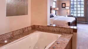 A hotel room with a large bathtub, a bed, a desk, and a window. - Park Plaza Condo W/Resort Amenities (Beaver Creek)