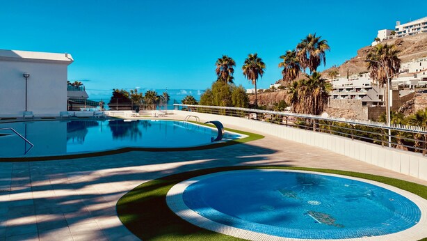 En swimmingpool med fri utsikt över havet och en vit byggnad i bakgrunden.
