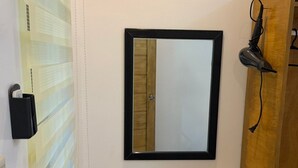 Un baño con tocador de madera, un espejo, un secador de pelo y un rollo de papel higiénico.