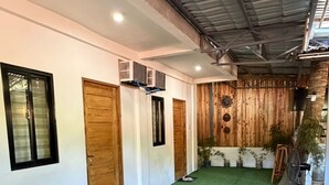 A hallway with artificial green flooring, wooden doors, and a metal ceiling. - Amazing property in (El Nido)