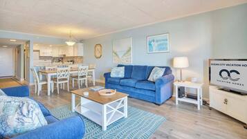 Een moderne woonkamer met een blauwe bank, een houten salontafel en een televisie op een meubel.
