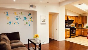 Ein Wohnzimmer mit einem braunen Sofa, einem Glastisch und einer Wand, die mit Kinderzahlen-Aufklebern dekoriert ist.